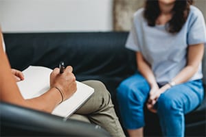 Smiling Casual Senior Woman Using Laptop While Talking On Smartphone.